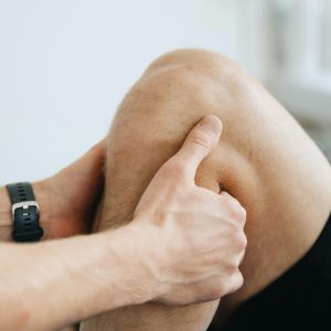 Close-up of a physiotherapist massaging a patient's knee during therapy.