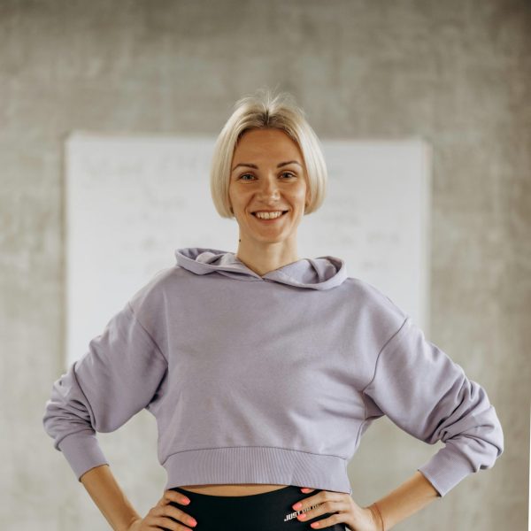 Confident woman in sportswear smiling indoors at the gym, embodying health and fitness.